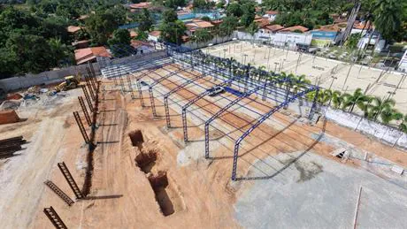 Galpão metálico em montagem com pórticos azuis